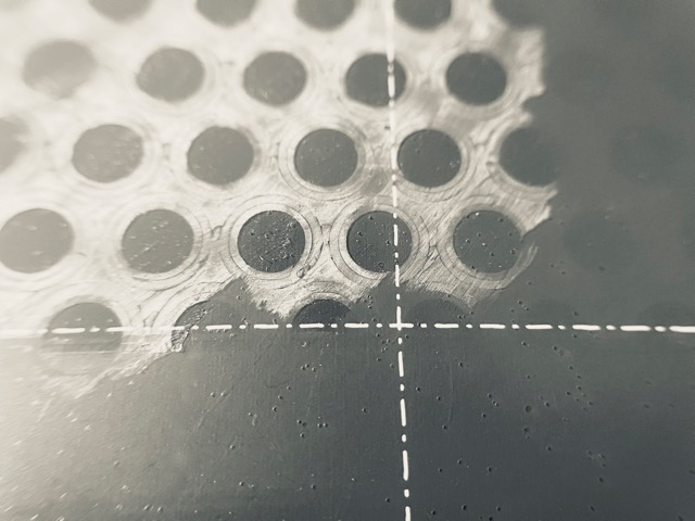 Close up of my 3D printer's build plate, with the partial layer of craft glue used for adhesion still present. (2026, color edited)